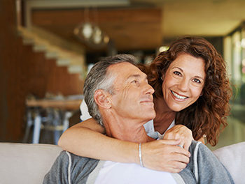 A very happy couple hugging on a sofa