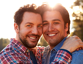 Two men embracing at sunset