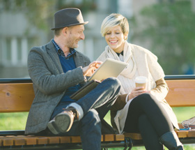 Older man talking to a younger woman on a park bench